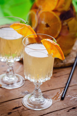 Glass of white sparkling wine sangria decorated with citrus slices and season fruits on wooden table.