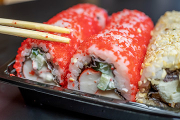 Wooden sticks lie on red sushi on a black background close-up. The concept of Japanese cuisine.