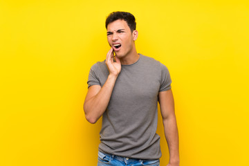 Handsome man over isolated yellow wall with toothache