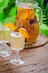 Glass of white sparkling wine sangria decorated with citrus slices and season fruits on wooden table.