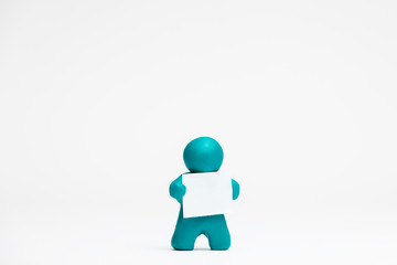 A man made from plasticine holding a blank sheet of paper on white background, aligned in the center.