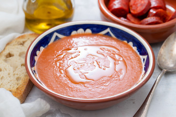 spanish soup gazpacho in bowl with bread and olive oil on ceramic background