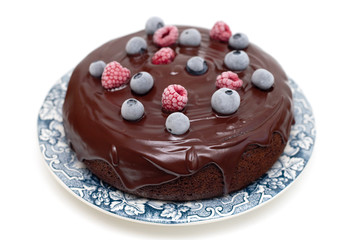 chocolate cake with frozen berries on plate on white background