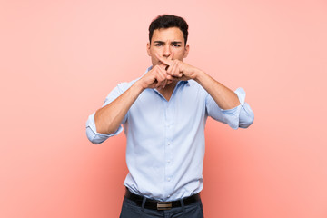 Handsome man over pink background showing a sign of silence gesture