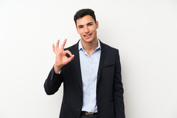 Handsome man over isolated white wall showing an ok sign with fingers