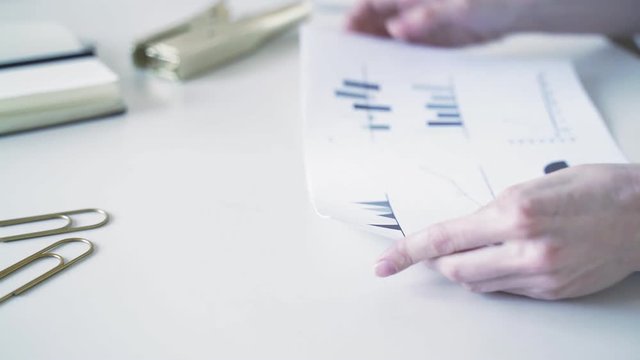Woman fills data in graphs on paper. Records information. Woman is engaged in office work. Graphic charts,indicators. Woman works at the offside table. Woman draws symbols on the paper