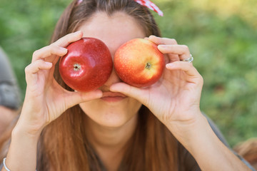 Girl with Apple in the Apple Orchard. Beautiful Girl Eating Organic Apple in the Orchard. Harvest Concept. Garden, teenager eating fruits at fall harvest