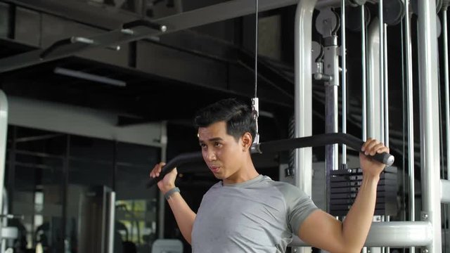 Lockdown of Asian man wearing sportswear pumping his arms in gym