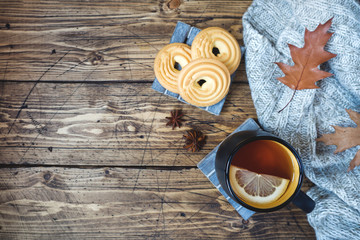 Autumn still life with cup of tea, cookies, sweater and leaves on wooden background. concept of cozy autumn, fall season