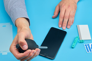 The man replacing the broken tempered glass screen protector for smartphone.