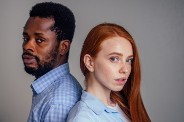 young redhead freckled woman hugging her African boyfriend, looking at the camera with happy face expression