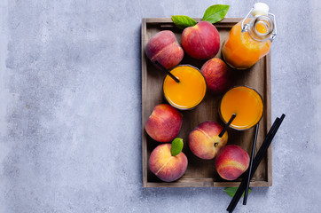 Fresh homemade peach juice in glass for breakfast on wooden tray over grey blue table Rustic stile.