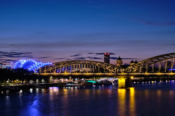 Fototapeta na wymiar Musical Dome und Hohenzollernbrücke in Köln, Blick über den Rhein während der blauen Stunde bei Nacht.