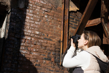 photographer takes pictures on camera against a brick wall