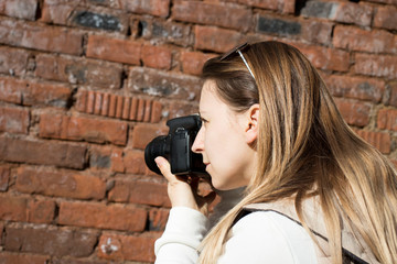 photographer takes pictures on camera against a brick wall