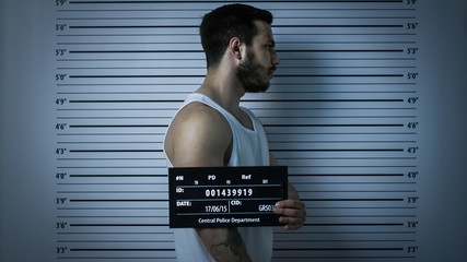 In a Police Station Arrested Beaten Man Poses for Side View Mugshot. He Wears Singlet, is Heavily...