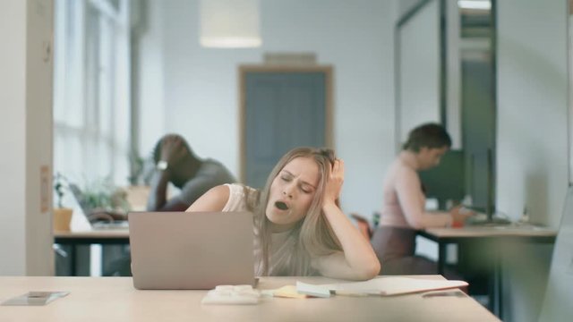 Tired woman sleeping with notebook at coworking office