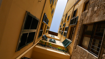 Fototapeta premium A view of a roofs from the narrow alley - yellow buildings and balcony
