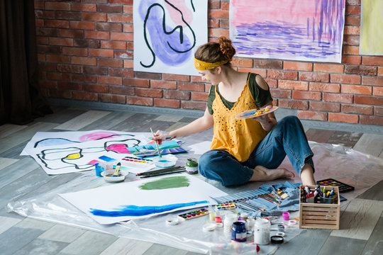 Modern Art School. Female Artist Sitting On Floor, Painting Abstract Artworks. Creative Workplace.