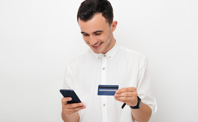 Happy young man is using mobile banking or buys something online on white background.