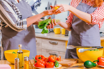 Vegetarian family lifestyle. Cropped shot of women cooking together, preparing salad with organic ingredients.