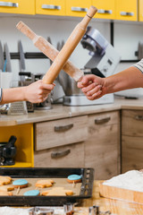 Chef tournament. Crossed rolling pins. Women playing fight in kitchen. Homemade biscuits on table.