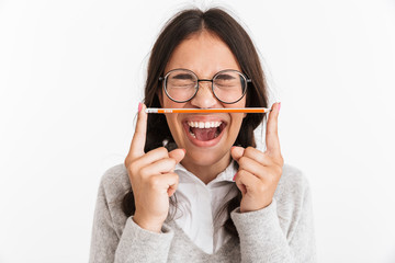 Excited emotional young school girl isolated over white wall background holding pencil.