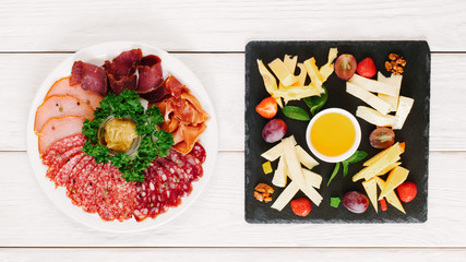 Professional catering. Flat lay of plates with cheese and meat assortment served on white wooden table.