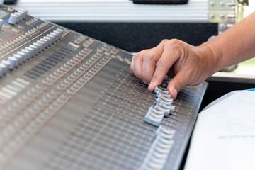 Closeup of hand adjust the professional audio digital mixing console. Selective focus