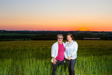 Couple poses at the end of the day out in the field with the beautiful landscape that nature presents with the sunset.