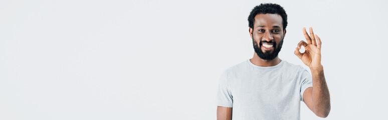 cheerful african american man in grey t-shirt showing ok sign isolated on grey