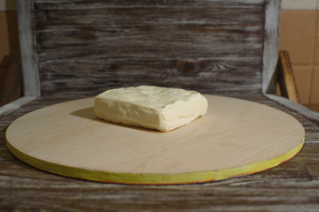 Stracchino cheese on a light wooden tray on a wooden background