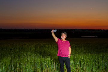 Man is taking a selfie at the end of the day out in the field with the beautiful landscape that nature presents with the sunset.