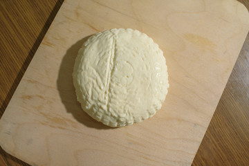 Fresh Adyghe cheese on a wooden tray on a wooden background