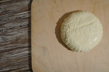 Fresh Adyghe cheese on a wooden tray on a wooden background