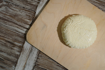 Fresh Adyghe cheese on a wooden tray on a wooden background