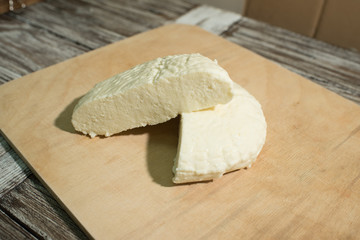 Fresh Adyghe cheese on a wooden tray on a wooden background