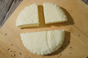 Fresh Adyghe cheese on a wooden tray on a wooden background