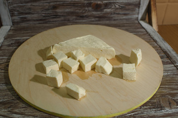 Stracchino cheese on a light wooden tray on a wooden background