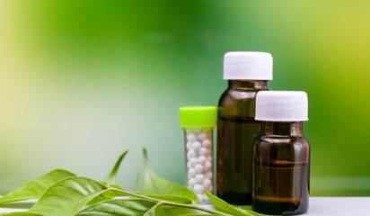 Homeopathy concept – Three bottles of homeopathy substance on green leaf with mix yellow green background