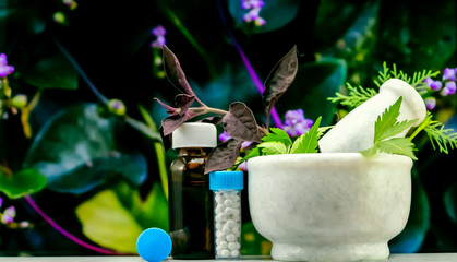 Natural Homeopathy Concept – Healing herbs in a mortar and pestle next to homeopathic medicine...