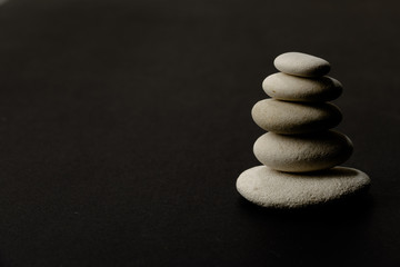 Fototapeta na wymiar stack of zen stones on the right side dark background and shadows