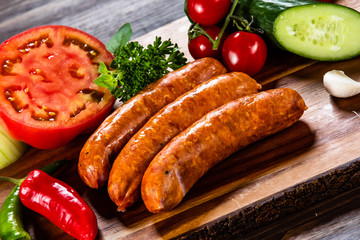 Raw sausages and vegetables on cutting board