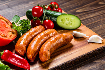 Raw sausages and vegetables on cutting board