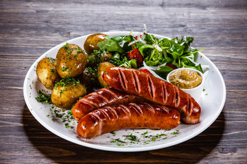 Grilled sausages, baked potatoes and vegetables