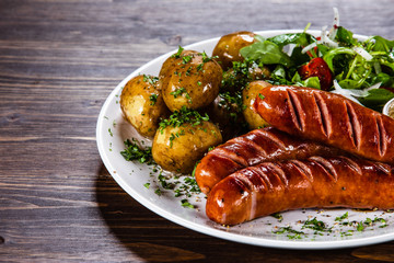 Grilled sausages, baked potatoes and vegetables