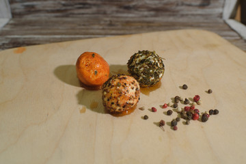 Orange, brown and black chevre cheese with spices on a wooden tray and wooden background