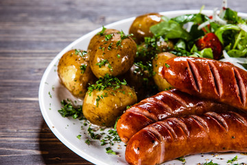 Grilled sausages, baked potatoes and vegetables