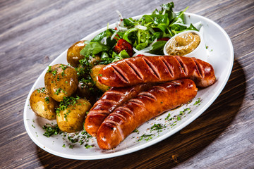 Grilled sausages, baked potatoes and vegetables