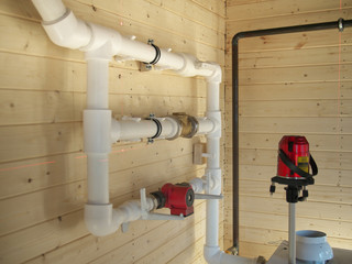 mounting of gravity heating system equipment with laser level in a boiler room. Circulation pump, stopcock, return valve, polypropylene tube and laser level